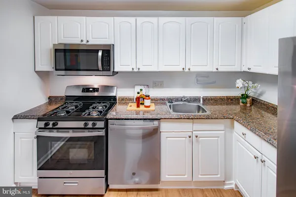 a kitchen with granite countertop white cabinets and stainless steel appliances