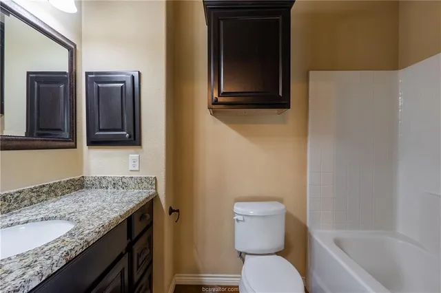 a bathroom with a granite countertop toilet sink and mirror