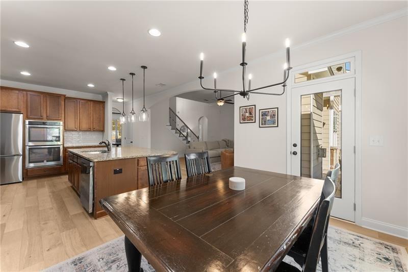 8055 Veranda Curve Ball Ground, GA 30107 - Photo 23 of 65 a kitchen with stainless steel appliances granite countertop a kitchen island a stove a refrigerator a sink a dining table and chairs with wooden floor