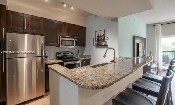 a kitchen with stainless steel appliances granite countertop a refrigerator and a stove top oven