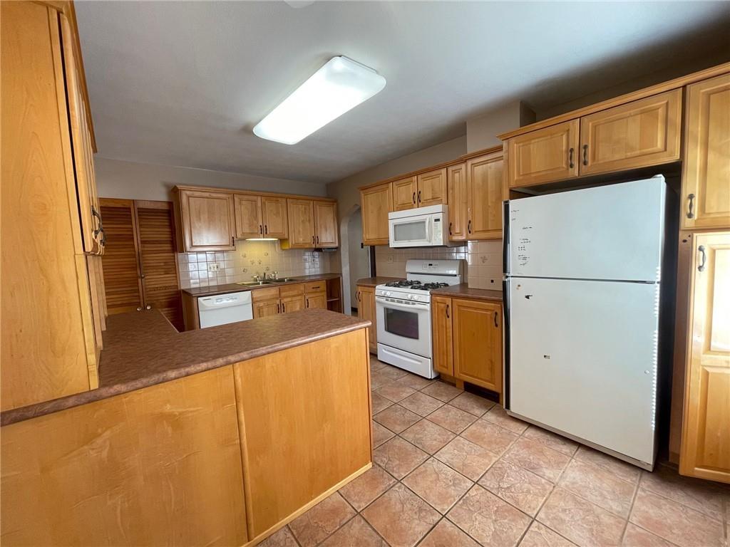 405 Routh Street Monroeville, PA 15146 - Photo 9 of 18 a kitchen with stainless steel appliances granite countertop a refrigerator a stove a sink dishwasher and a refrigerator with wooden cabinets
