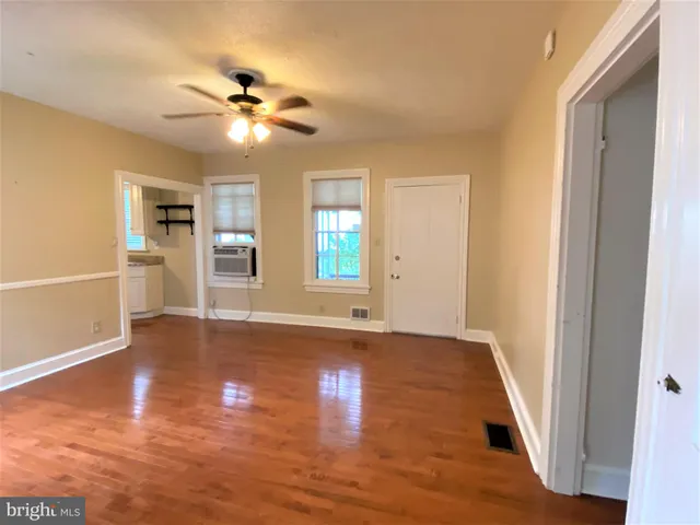 a view of an empty room with wooden floor and a window