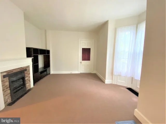 a view of an empty room with a fireplace and a window