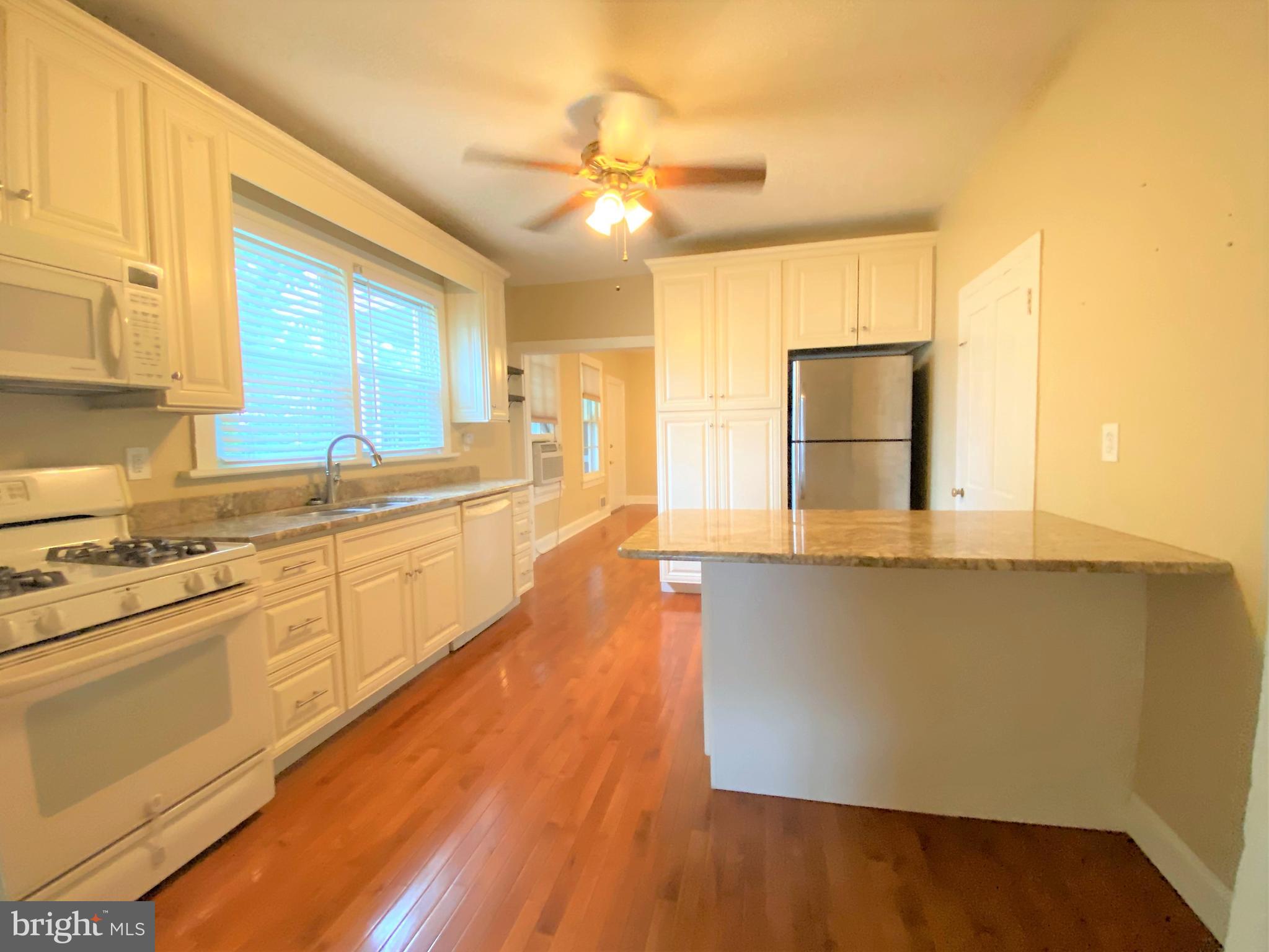 200 Broad Street Mount Holly, NJ 08060 - Photo 8 of 19 a large kitchen with stainless steel appliances a large window a oven and white cabinets with wooden floor