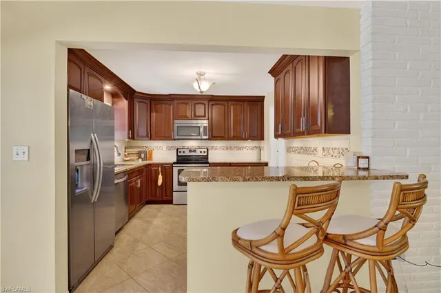 a kitchen with stainless steel appliances granite countertop a stove top oven a sink dishwasher a dining table and chairs