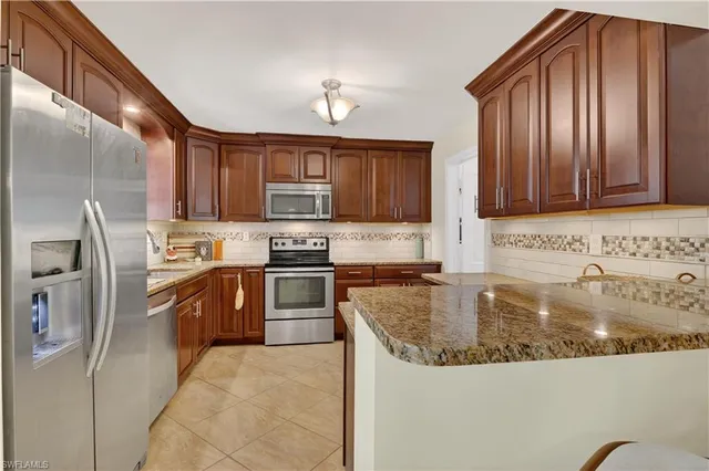 a kitchen with stainless steel appliances granite countertop a sink refrigerator stove and microwave