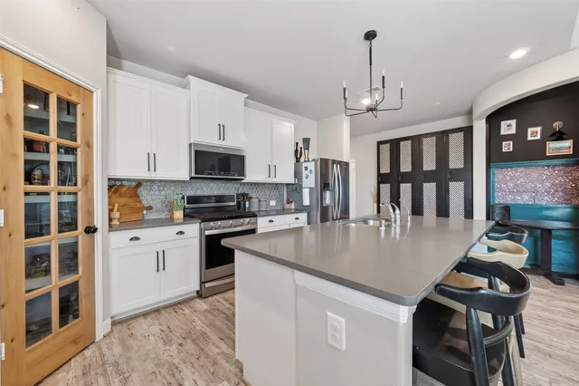 a kitchen with a stove a sink dishwasher a dining table and chairs with wooden floor