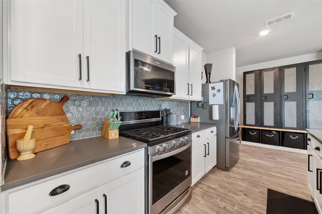 a kitchen with stainless steel appliances granite countertop a stove a sink and a microwave