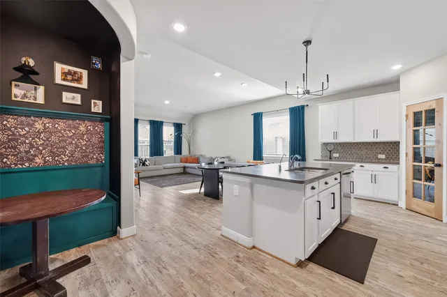 a kitchen with stainless steel appliances granite countertop a stove top oven a sink dishwasher and a refrigerator with wooden floor