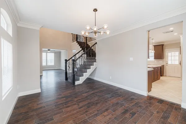 an empty room with wooden floor cabinet and windows