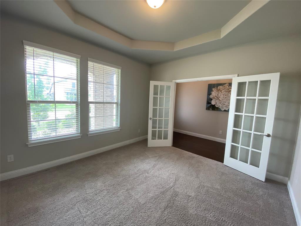 209 Johnson Street Granbury, TX 76048 - Photo 21 of 40 Unfurnished room featuring french doors, dark colored carpet, and a tray ceiling