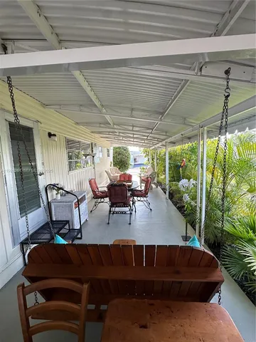 a view of a patio with table and chairs potted plants with floor to ceiling window and potted plants