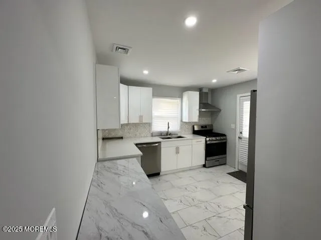 a view of a kitchen with a sink and dishwasher a refrigerator with white cabinets