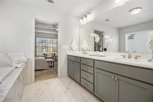a en suite bathroom with a double vanity sink a mirror and a bathtub