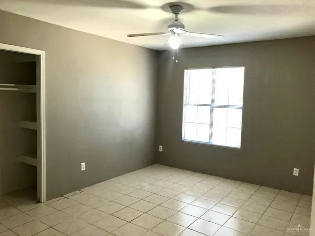an empty room with windows and chandelier fan
