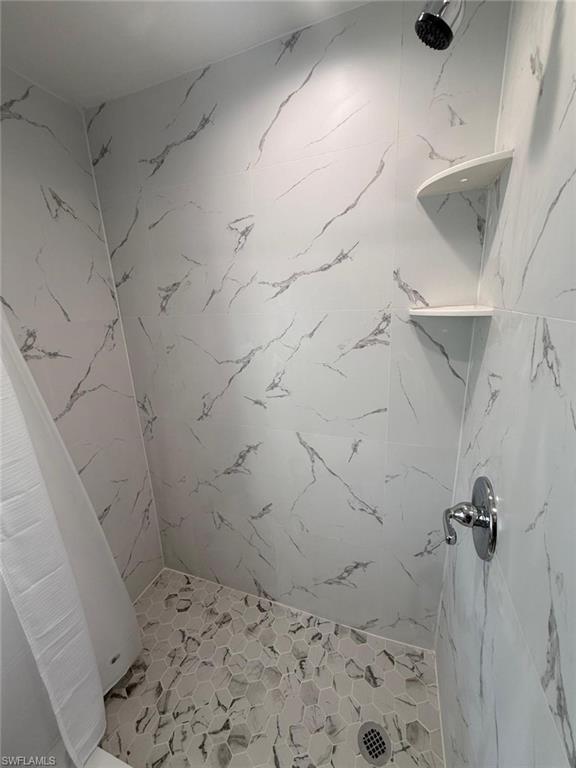 5317 Fleming Street Naples, FL 34113 - Photo 5 of 8 Tiled shower with white and grey marbled-pattern walls