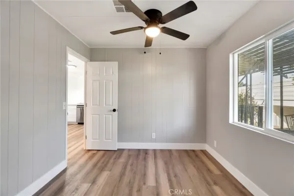 a view of an empty room with a window and wooden floor