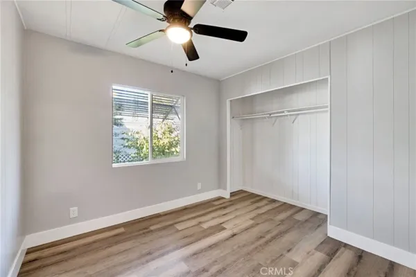 a view of empty room with wooden floor and fan