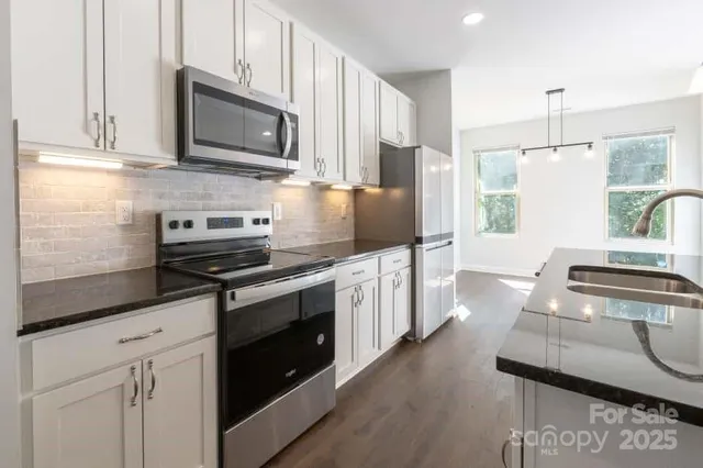 a kitchen with stainless steel appliances a stove microwave and sink