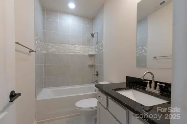 a bathroom with a granite countertop sink toilet a mirror and shower
