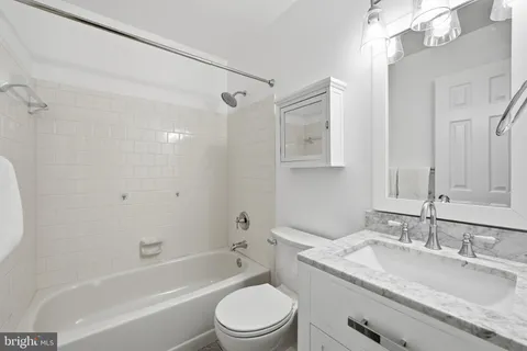 a bathroom with a granite countertop sink a toilet and shower