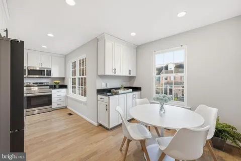 a kitchen with a table chairs a sink dishwasher stove and cabinets with wooden floor