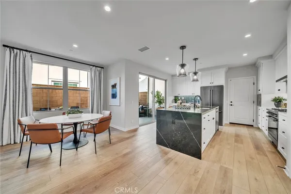 a living room with stainless steel appliances granite countertop furniture wooden floor and a rug