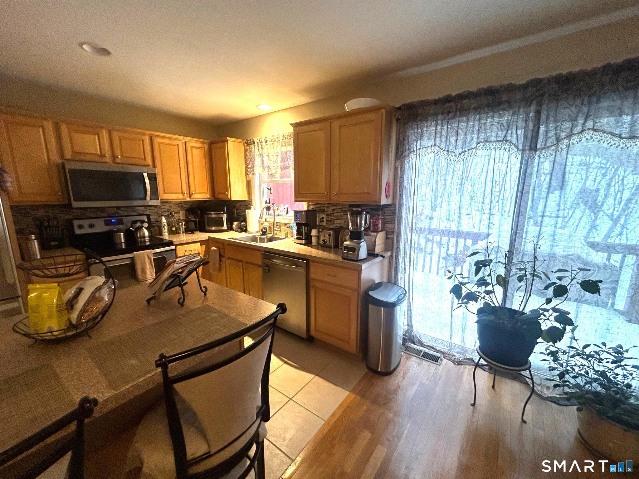 194 Summit Street Norwich, CT 06360 - Photo 3 of 24 a kitchen with a stove a sink a microwave a dining table and chairs