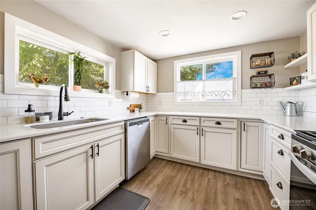 a kitchen with white cabinets a window and sink