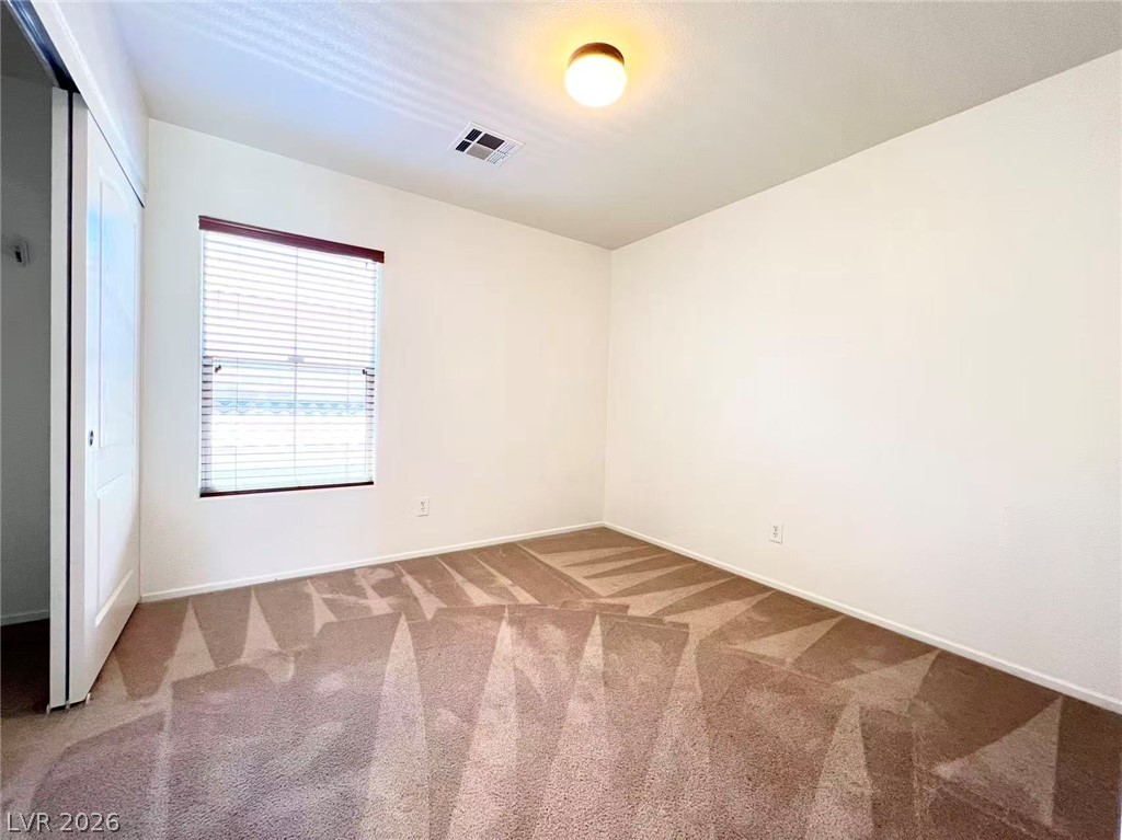 11143 Ranch Valley Street Las Vegas, NV 89179 - Photo 21 of 23 A well-lit bedroom features plush carpeting and abundant natural light from the window.