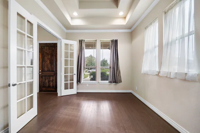 an empty room with wooden floor and windows