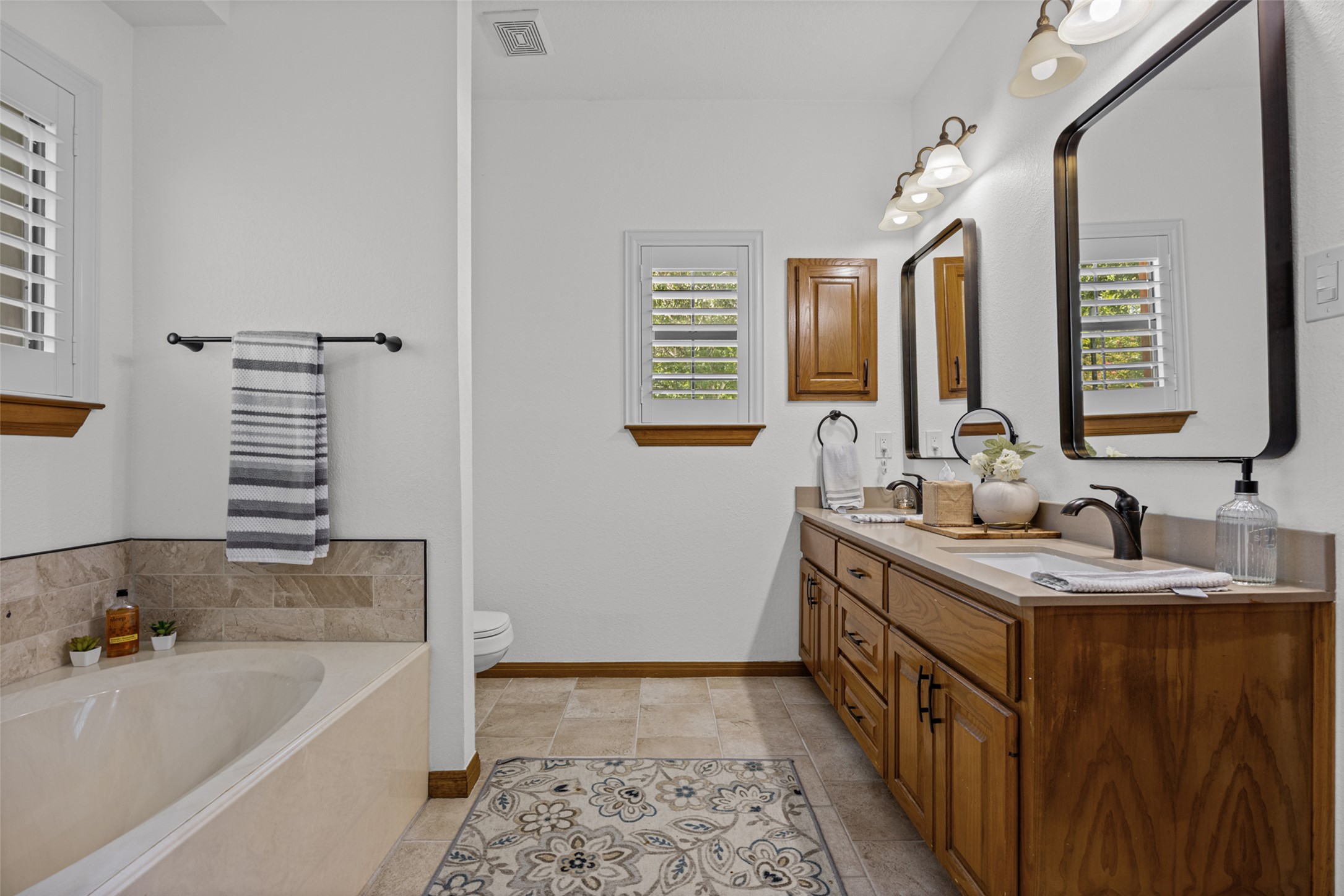 2000 Spinel Road Pflugerville, TX 78660 - Photo 17 of 31 A well-lit primary bathroom features a generous soaking tub, dual vanities, and a private water closet.