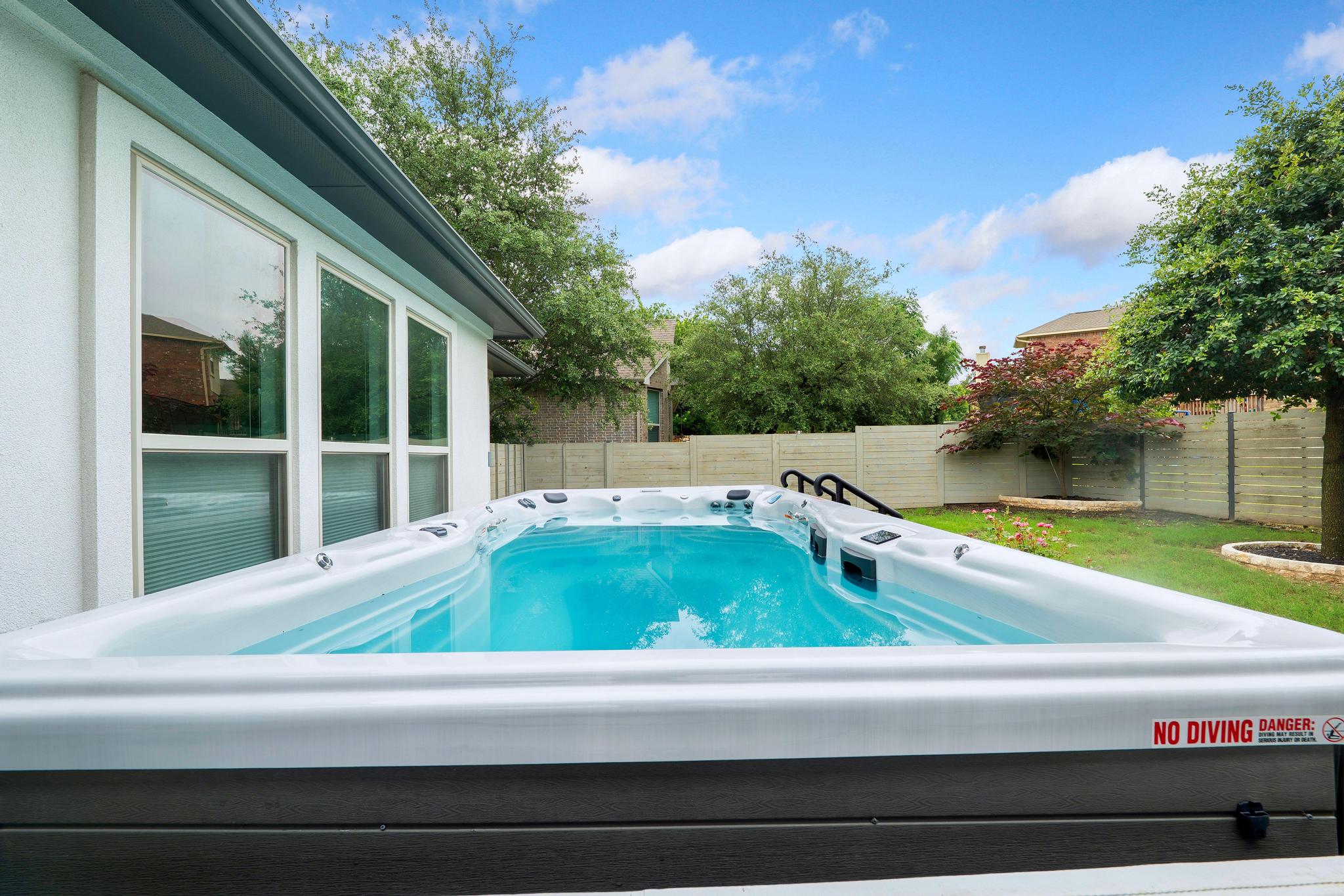 1009 Legacy Crossing Georgetown, TX 78628 - Photo 36 of 40 A private backyard oasis features a glistening spa alongside a pristine white-walled structure and lush green landscaping.