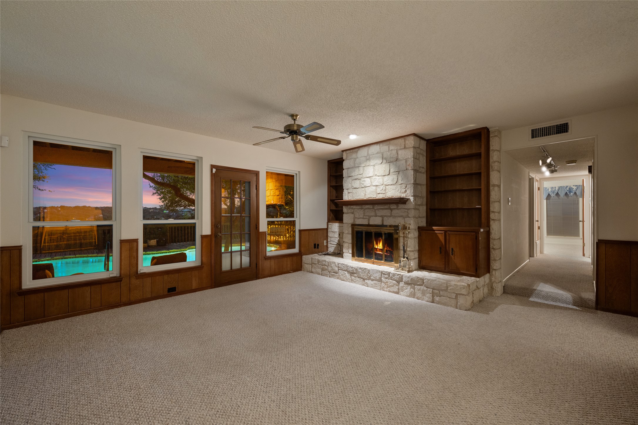 5319 Musket Ridge Austin, TX 78759 - Photo 11 of 39 A cozy living space features a stone fireplace, built-in shelving, and direct access to an outdoor area with a pool.