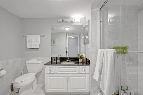 a bathroom with a granite countertop sink a toilet and a mirror