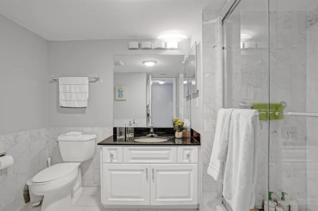 a bathroom with a granite countertop sink a toilet and a mirror