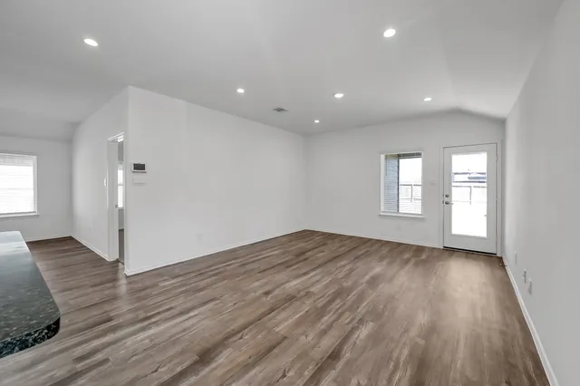 a view of empty room with window and wooden floor