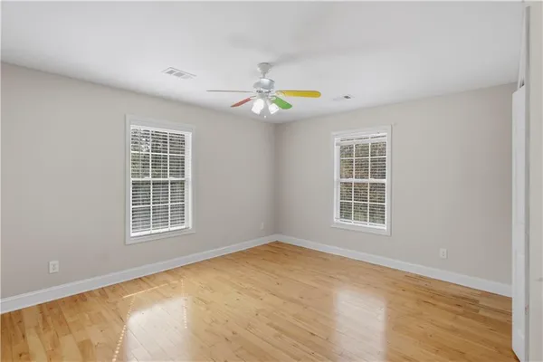 an empty room with wooden floor and windows
