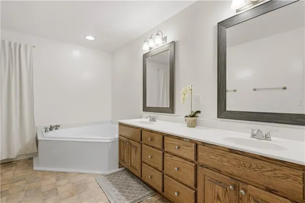 a bathroom with a double vanity sink large mirror and bathtub