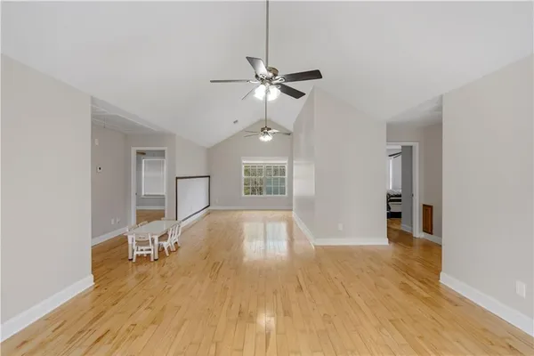 a view of empty room with wooden floor and fan