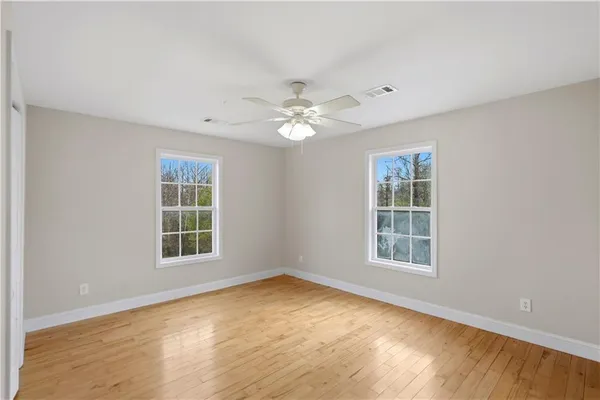 an empty room with windows and ceiling fan