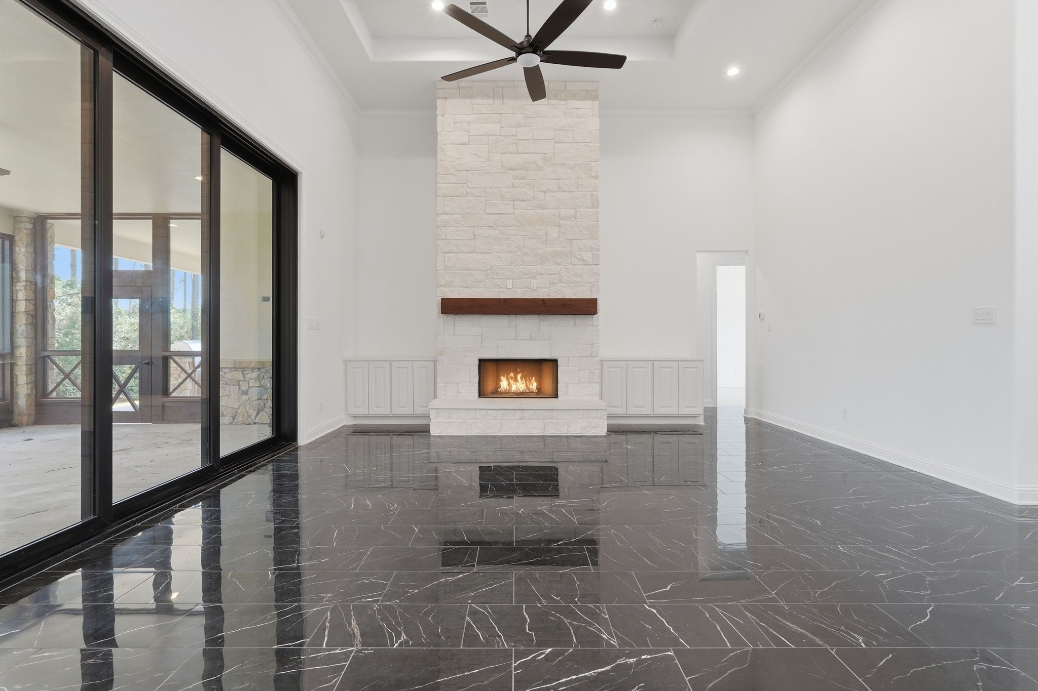 16081 Forest Mill Road Willis, TX 77378 - Photo 7 of 37 Spacious family room featuring soaring ceilings, a striking stone fireplace, and oversized glass doors that seamlessly connect indoor and outdoor living.