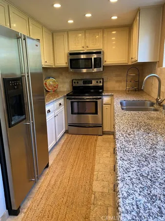 a kitchen with granite countertop a refrigerator and a stove top oven