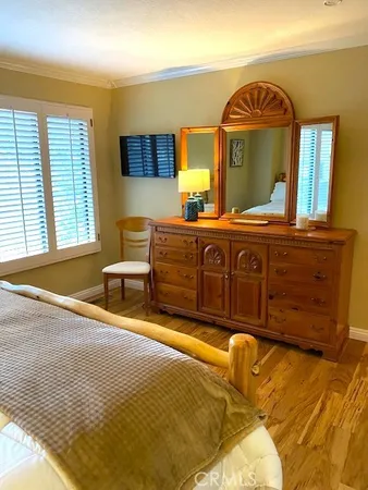 a spacious bedroom with a bed a dresser and mirror