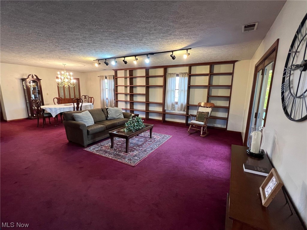 36555 Flat Rock Road Barnesville, OH 43713 - Photo 6 of 35 Carpeted living room featuring an inviting chandelier, track lighting, and a textured ceiling