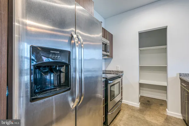 a kitchen with stainless steel appliances kitchen island granite countertop a refrigerator and a sink