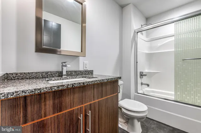 a bathroom with a granite countertop sink mirror vanity and toilet
