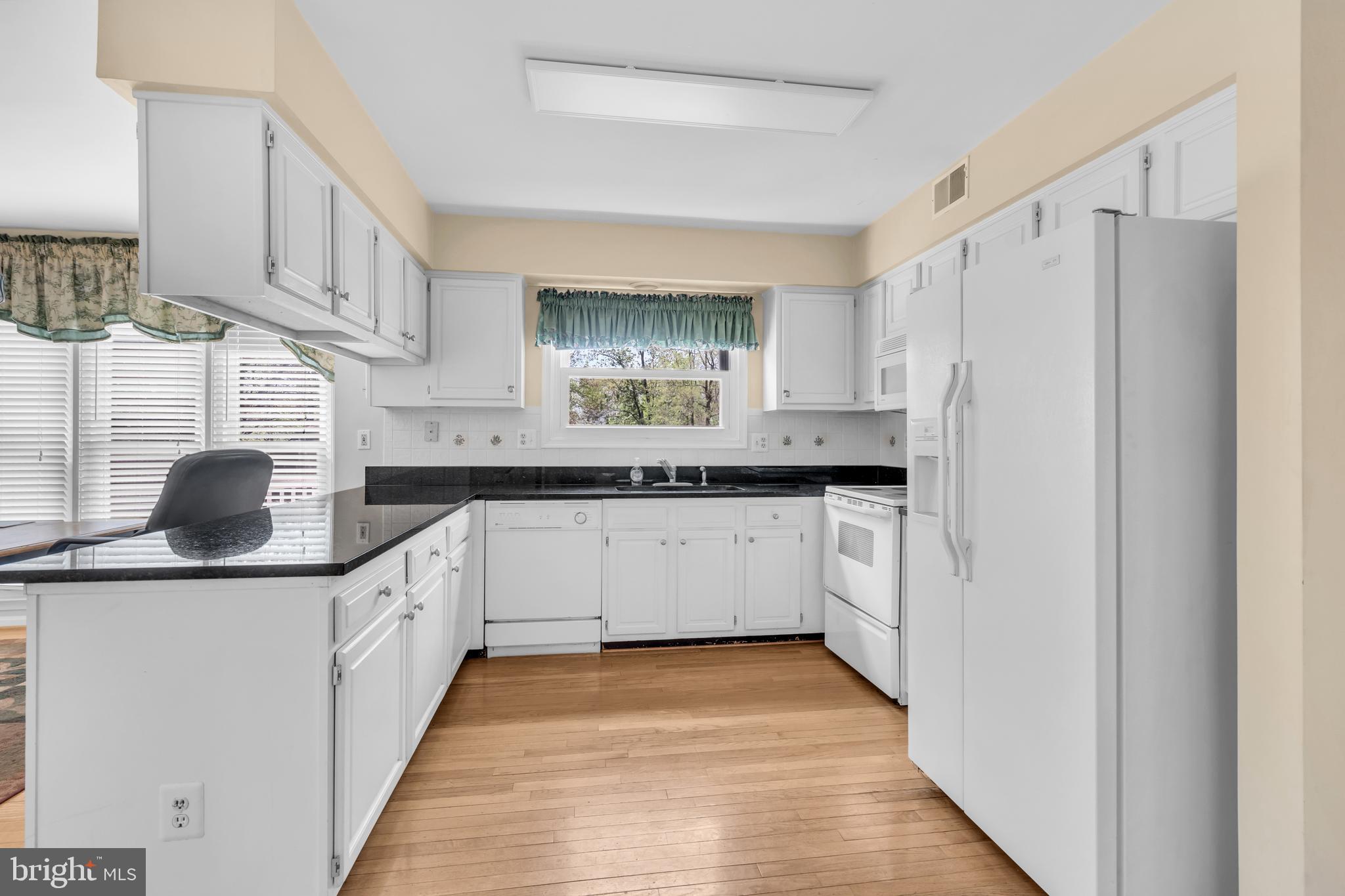 13988 Dancing Twig Drive Gainesville, VA 20155 - Photo 15 of 62 a kitchen with granite countertop a white refrigerator oven a sink dishwasher and white cabinets with wooden floor