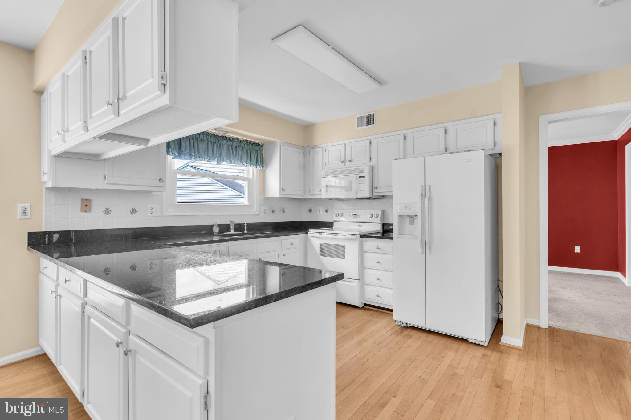 13988 Dancing Twig Drive Gainesville, VA 20155 - Photo 17 of 62 a kitchen with granite countertop white cabinets and stainless steel appliances