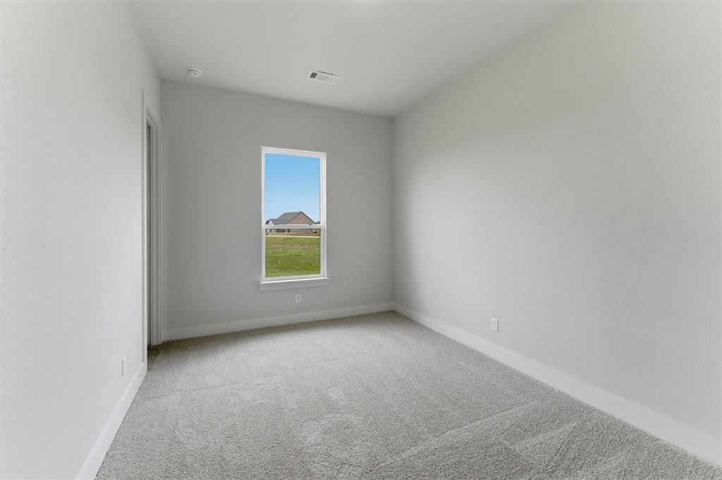 2204 Continent Court Krum, TX 76249 - Photo 20 of 28 Neutral color palette with textured walls, light-toned carpeting, and a single window with a white frame